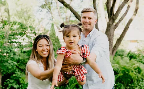 Parents holding up their smiling toddler.