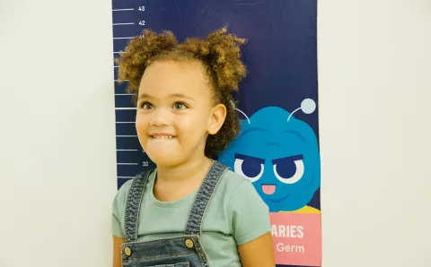 A pediatric dental patient measuring how tall she is while at her dental appointment.